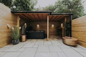 a wooden pergola with a tub in a patio at Clifton 32 - Garden Flat with Hot Tub - Hopewell in Bristol