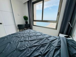 sypialnia z łóżkiem i dużym oknem w obiekcie Luxurious Beach apartment w mieście Hajfa