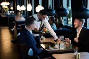 a waiter serving two men at a table in a restaurant at Scandic Norreport in Copenhagen