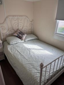 1 dormitorio con 1 cama con cabecero blanco y ventana en Chalet 24 en Leysdown-on-Sea