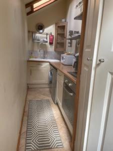 uma pequena cozinha com um lavatório e um fogão em Cobwebs em Kedington