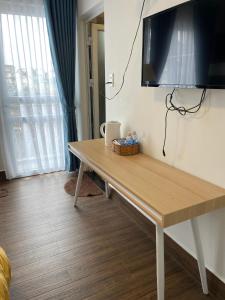 uma mesa de madeira num quarto com uma televisão na parede em My House Hotel em Da Lat