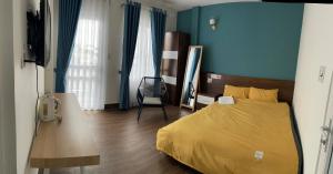 um quarto com uma cama amarela e paredes azuis em My House Hotel em Da Lat
