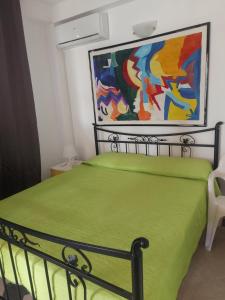 馬里納－迪拉古薩的住宿－A casa di Franco，卧室配有一张绿色的床,墙上挂有绘画作品