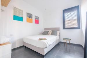 a white bedroom with a bed and a stool at Ninai Sea Holiday Apartment 2 in Furci Siculo