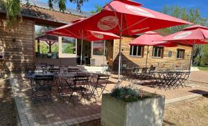 a restaurant with tables and chairs with red umbrellas at Camping de Messeugne 