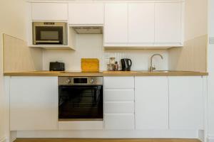 uma cozinha com armários brancos, um lavatório e um micro-ondas em Grange Rd Flat 2 one bedroom flat em Bristol