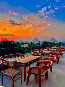 een rij tafels en banken op een balkon met een zonsondergang bij Almas Pyramids Hotel in Caïro