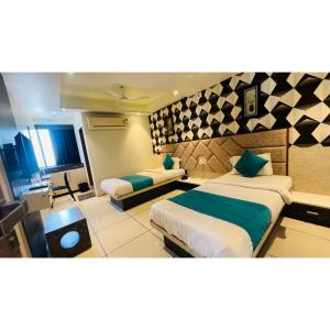 Habitación de hotel con 2 camas y escritorio en Hotel Sigma en Ahmedabad