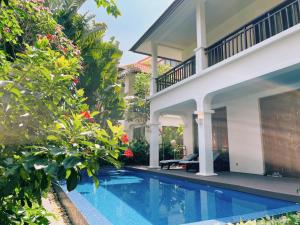 a villa with a swimming pool in front of a house at Tropical Pool Villas Da Nang in Da Nang