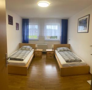 Cette chambre comprend 2 lits et une fenêtre. dans l'établissement Ferienwohnung "Zwei Birken", à Ellwangen