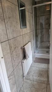 baño con ducha con toalla y puerta de cristal en Penbryn Holidays, Barmouth en Barmouth