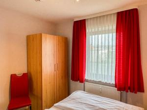 Schlafzimmer mit einem Bett und einem Fenster mit roten Vorhängen in der Unterkunft Haus Nordseeblick Wohnung 9 in Büsum