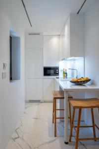 eine weiße Küche mit einem Tisch und 2 Hockern in der Unterkunft Numi Suites in Mykonos Stadt