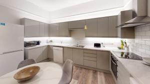 a kitchen with white cabinets and a wooden table at Queens road seven bedroom flat in Bristol