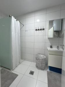 een witte badkamer met een douche en een wastafel bij City Center 1bedroom in Ferizaj