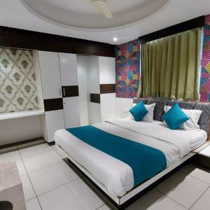 a bedroom with a large bed with blue pillows at Hotel Sigma in Ahmedabad