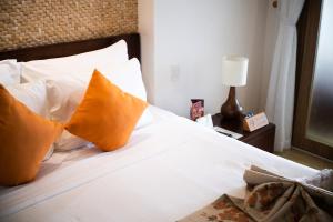 a bedroom with a bed with white sheets and orange pillows at The Cliff Residence in Mui Ne