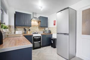 a kitchen with blue cabinets and a white refrigerator at Deerness Viewpoint-Your Scenic Retreat in Brandon in Durham