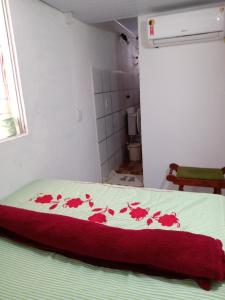 uma cama com flores vermelhas num quarto em Kitnet aconchegante em Olinda