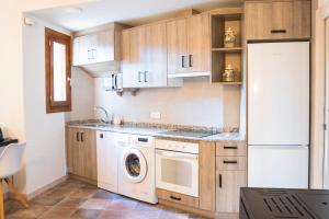 a kitchen with wooden cabinets and a washer and dryer at El Rincón de Alquézar in Alquézar