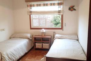 two beds in a small room with a window at Casa a piorneira in Teo