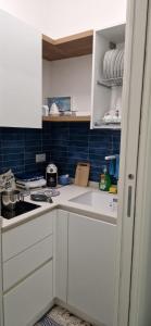 uma cozinha com armários brancos e azulejos azuis em Casa Vacanze Marinella Beach em San Vito lo Capo