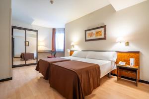 Pokój hotelowy z łóżkiem i lustrem w obiekcie Hotel Glòries w Barcelonie