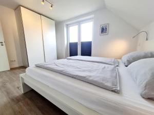 a large white bed in a room with a window at Sandbank in Sankt Peter-Ording