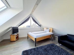 ein Schlafzimmer mit einem Bett, einem TV und einem Sofa in der Unterkunft Sandbank in Sankt Peter-Ording