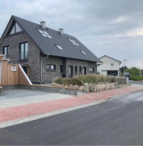 a brick house with a black roof on a street at Sandbank in Sankt Peter-Ording