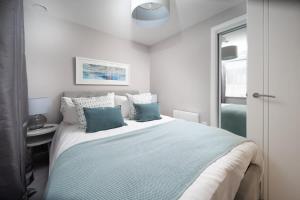 1 dormitorio con 1 cama grande con almohadas azules y blancas en Deluxe Apartment near Cabot Circus w Parking sleeps 5 en Bristol