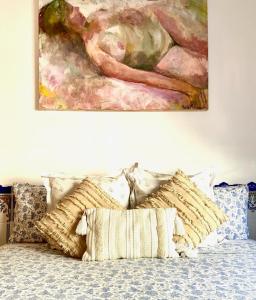 a painting hanging on a wall above a bed with pillows at Zenit Olhao Bed & Breakfast in Olhão