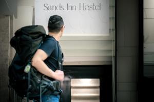 a man with a backpack standing in front of a sign at Sands Inn Hostel - City Center in Riyadh