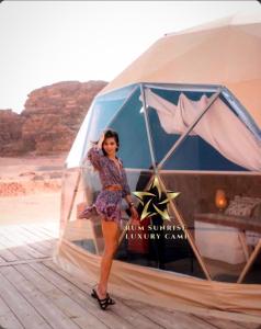 a woman is standing in front of a tent at RUM SUNRlSE LUXURY CAMP in Wadi Rum