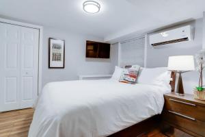 a white bedroom with a large bed and a lamp at Beautiful 2 Bedroom across from The House of Representatives in Washington