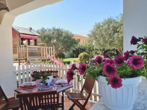 een tafel met bloemen in een witte vaas op een patio bij Villa Calipso - Appartamento in Villa con giardino e wi-fi in Ovile la Marinella