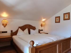 a bedroom with a large bed with white sheets at Apartments im Jagdhof in Fischen