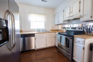 a kitchen with white cabinets and a stainless steel refrigerator at Sojourn Tree Lined Streets Newport News in Newport News