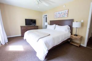 a bedroom with a large white bed and a television at Sojourn Tree Lined Streets Newport News in Newport News
