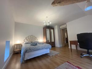 a bedroom with a bed and a desk and a chair at Al Bioule - Maison climatisée avec piscine in Penne-dʼAgenais
