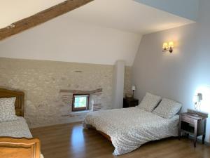 a bedroom with two beds and a stone wall at Al Bioule - Maison climatisée avec piscine in Penne-dʼAgenais