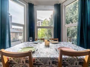 een eetkamer met een tafel en grote ramen bij Elegant bright flat free parking Pass the Keys in Kingston upon Thames