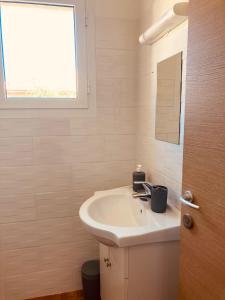 un bagno bianco con lavandino e finestra di Punta di Mare a Linguizzetta