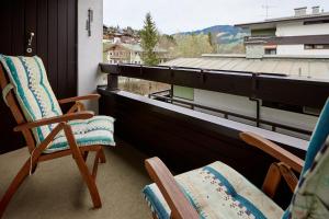 - un balcon avec deux chaises et une vue sur un bâtiment dans l'établissement Fereinwohnung Flussrauschen, à Kirchberg in Tirol