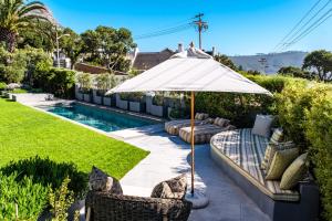een patio met een parasol en stoelen en een zwembad bij Oranjezicht Heritage Home in Kaapstad