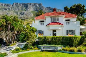 een wit huis met een rood dak en bergen op de achtergrond bij Oranjezicht Heritage Home in Kaapstad