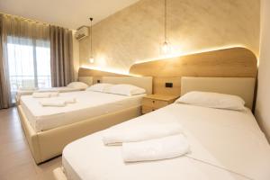 Habitación de hotel con 2 camas con sábanas blancas en Hotel Klebrido en Durrës