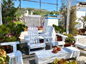 um grupo de cadeiras brancas num deque com plantas em Casa da Aldeia em Santa Bárbara de Nexe