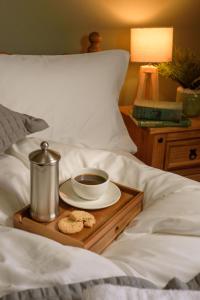 a tray with a cup of coffee and cookies on a bed at The Downe Arms Hotel in Castleton